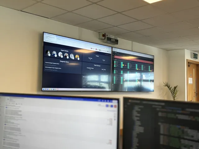 Operations dashboards on a wall of screens in the Next2IT office