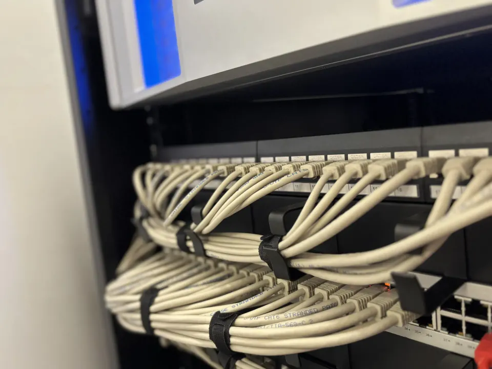 Network patch panels and switches connected with neatly bundled cream Ethernet cables.